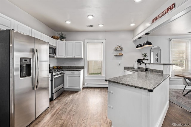 3464 S Downing St, Englewood, CO 80113 - kitchen with appliances with stainless steel finishes, a peninsula, dark wood-style flooring, white cabinetry, and recessed lighting