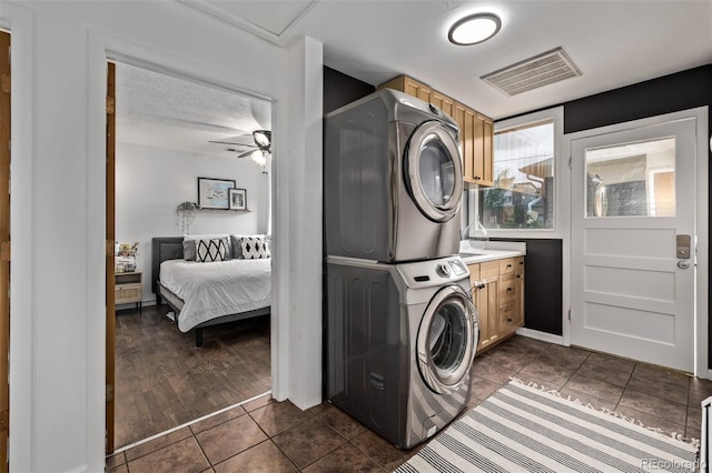 3464 S Downing St, Englewood, CO 80113 - laundry room featuring cabinet space, stacked washing machine and dryer, dark tile patterned flooring, and a ceiling fan