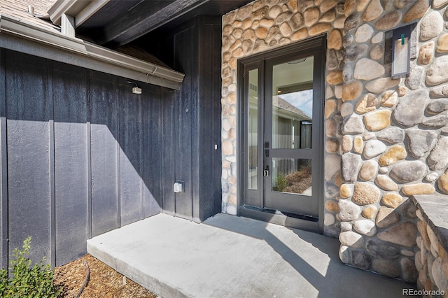 property entrance with board and batten siding and stone siding