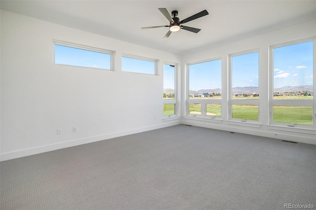 unfurnished sunroom featuring visible vents, a wealth of natural light, and ceiling fan