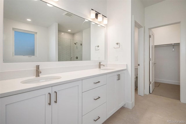 full bathroom with double vanity, a stall shower, toilet, and a sink