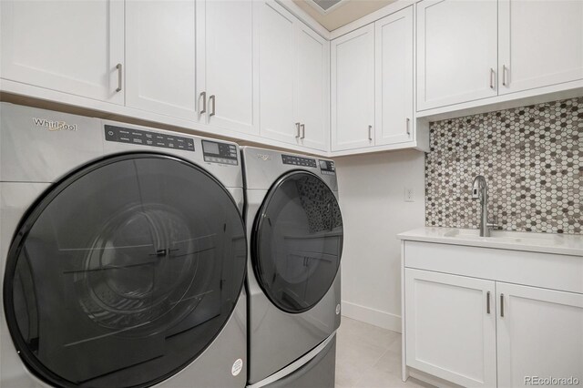 laundry room with a sink, baseboards, light tile patterned flooring, cabinet space, and separate washer and dryer