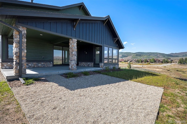 rear view of house with a mountain view, board and batten siding, and stone siding