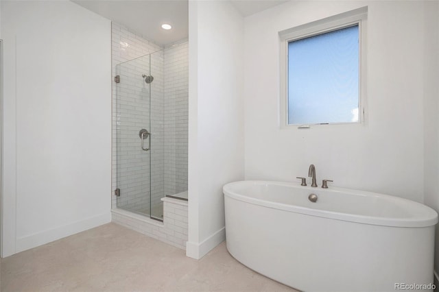 bathroom featuring a shower stall, a freestanding bath, and baseboards