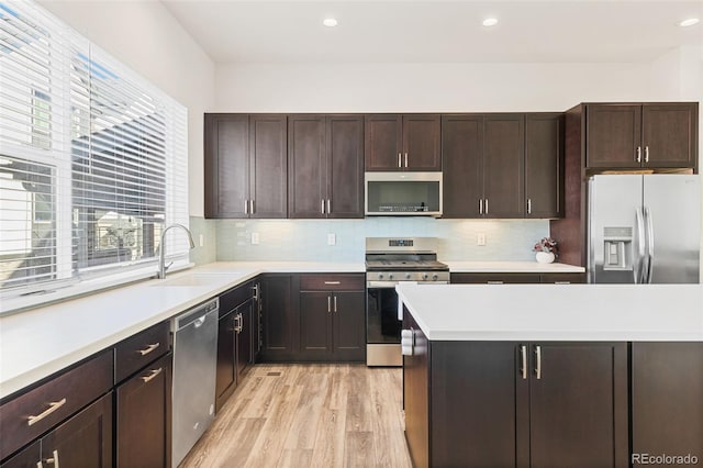 5173 Vivian St, Wheat Ridge, CO 80033 - kitchen featuring stainless steel appliances, a sink, light wood-type flooring, light countertops, and decorative backsplash