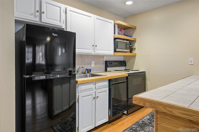 kitchen with tile countertops, black appliances, sink, tasteful backsplash, and white cabinetry