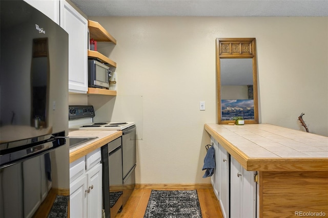 kitchen with white cabinets, refrigerator, range with electric stovetop, and tile countertops