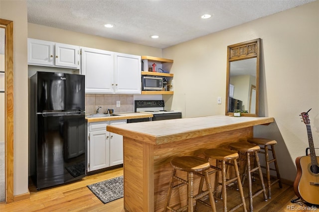 kitchen featuring tile countertops, black refrigerator, white cabinets, and white electric stove