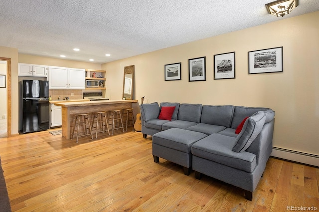 living room featuring a textured ceiling, light wood-type flooring, and a baseboard radiator