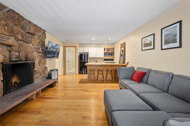 living room featuring a fireplace, light hardwood / wood-style flooring, and a textured ceiling