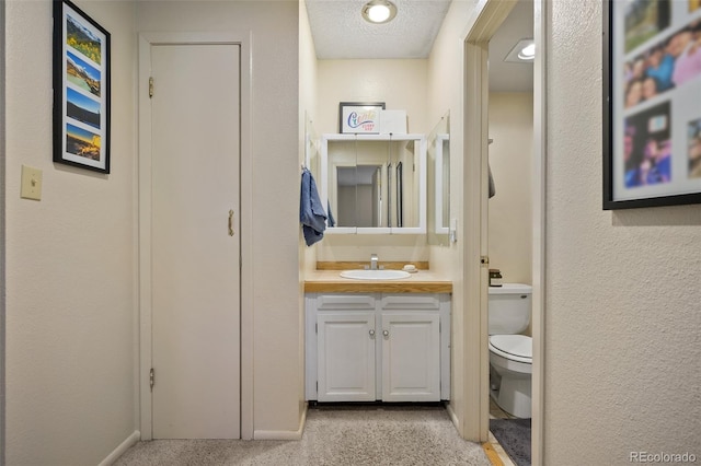 bathroom featuring vanity, toilet, and a textured ceiling