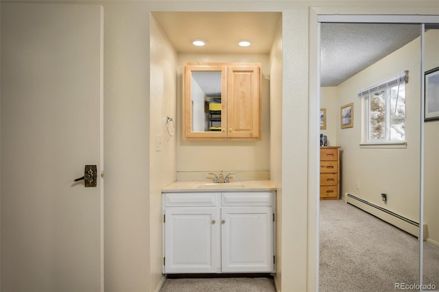 bathroom with vanity, a textured ceiling, and a baseboard heating unit