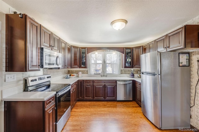 306 E Cannon St, Lafayette, CO 80026 - kitchen with glass insert cabinets, light countertops, a sink, light wood finished floors, and appliances with stainless steel finishes