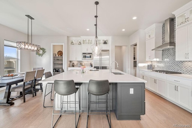 5390 Edenborn Way, Castle Rock, CO 80104 - kitchen featuring wall chimney exhaust hood, stainless steel appliances, tasteful backsplash, glass insert cabinets, and an island with sink