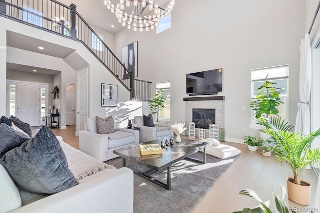 5390 Edenborn Way, Castle Rock, CO 80104 - living area featuring a towering ceiling, wood finished floors, healthy amount of natural light, a chandelier, and a glass covered fireplace