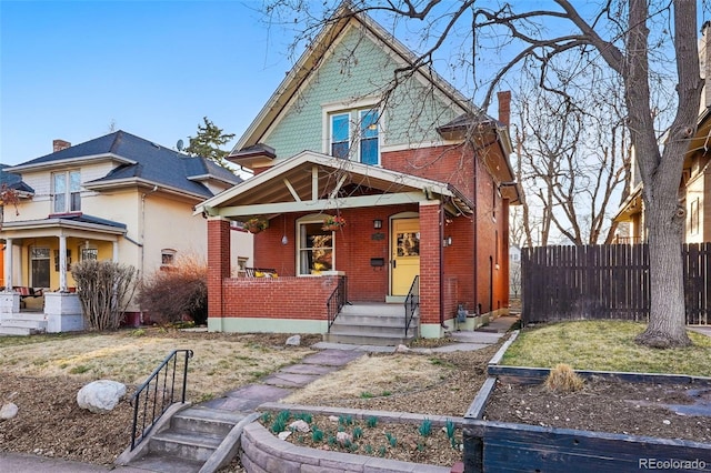 view of front of home with brick siding, a porch, and fence