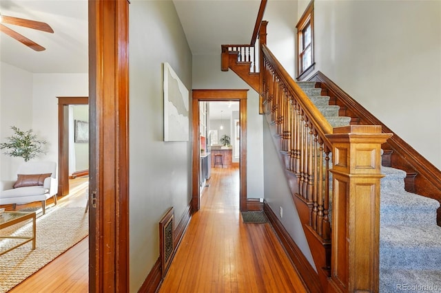 interior space featuring hardwood / wood-style flooring, a ceiling fan, visible vents, and baseboards