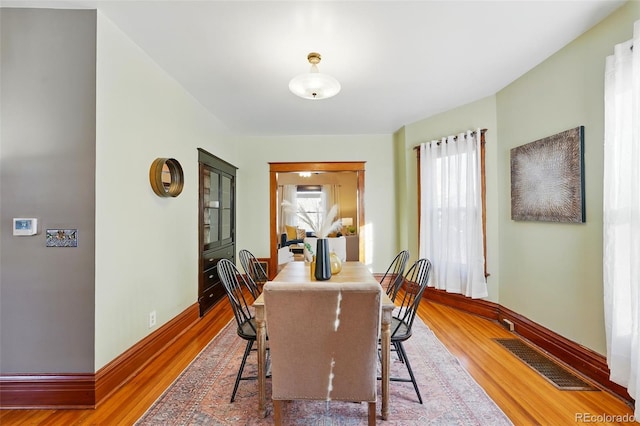 dining area with visible vents, baseboards, and wood finished floors