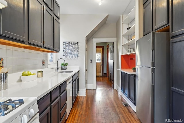 kitchen with backsplash, light countertops, freestanding refrigerator, dark wood-style floors, and a sink