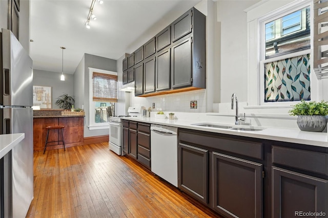 kitchen with white appliances, a sink, light countertops, light wood-style floors, and tasteful backsplash