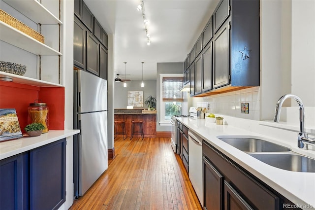 kitchen with open shelves, dishwasher, range, freestanding refrigerator, and a sink