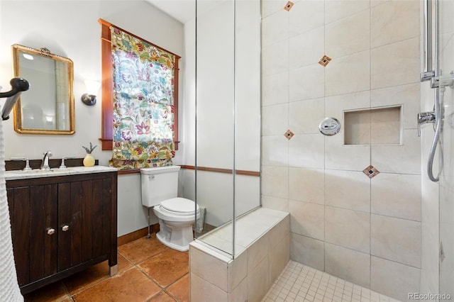 bathroom with vanity, tile patterned floors, toilet, and tiled shower