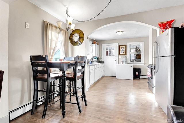 dining room featuring light hardwood / wood-style flooring, baseboard heating, and a notable chandelier