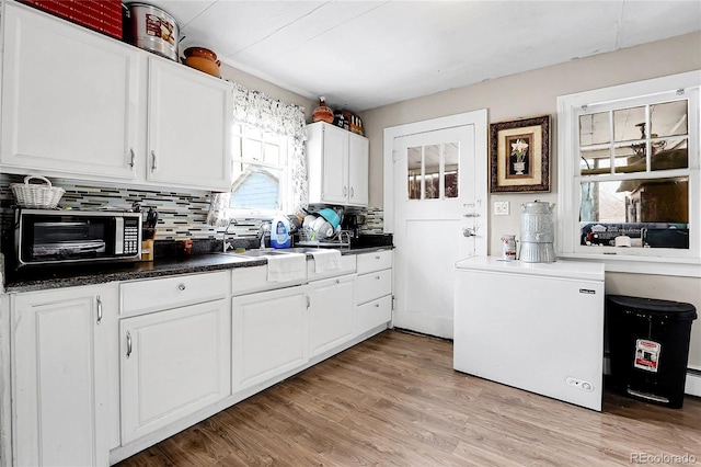 kitchen with refrigerator, backsplash, sink, light hardwood / wood-style flooring, and white cabinets