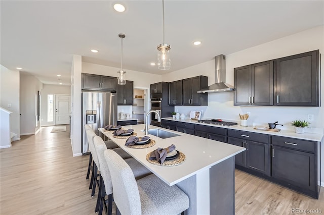 kitchen featuring a sink, wall chimney exhaust hood, appliances with stainless steel finishes, and light countertops