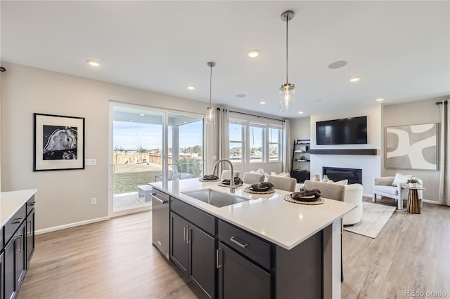 kitchen featuring light countertops, hanging light fixtures, a sink, and a center island with sink