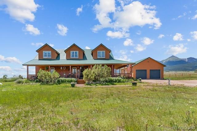 28 County Road 136, Westcliffe, CO 81252 - farmhouse with a porch, an attached garage, concrete driveway, a mountain view, and metal roof