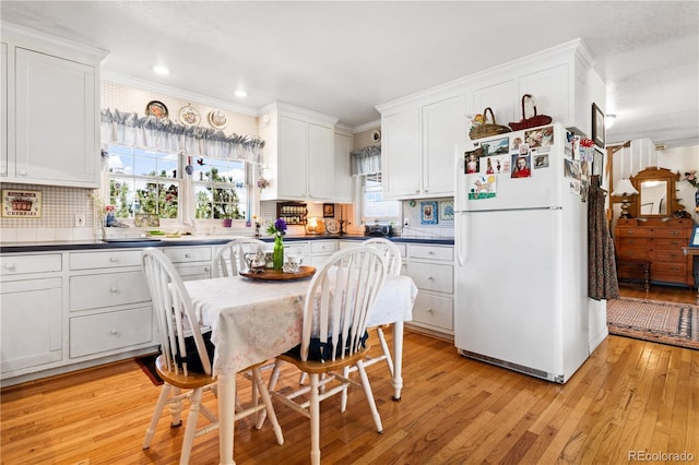 kitchen featuring white cabinetry, white refrigerator, tasteful backsplash, crown molding, and light hardwood / wood-style flooring