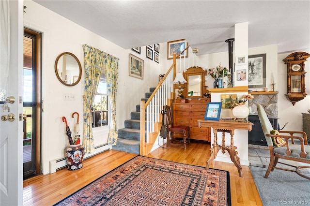 entryway featuring a baseboard heating unit, a wood stove, and light hardwood / wood-style floors