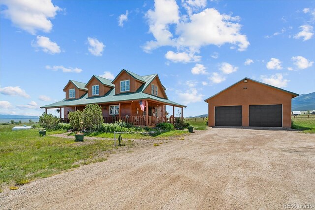 view of front of house with covered porch, an outbuilding, and a garage