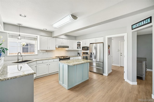 6565 W 99th Ave, Broomfield, CO 80021 - kitchen featuring backsplash, a sink, under cabinet range hood, stainless steel appliances, and white cabinetry