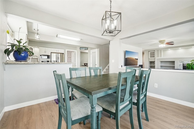 6565 W 99th Ave, Broomfield, CO 80021 - dining area featuring baseboards, light wood-style flooring, ceiling fan with notable chandelier, and built in features