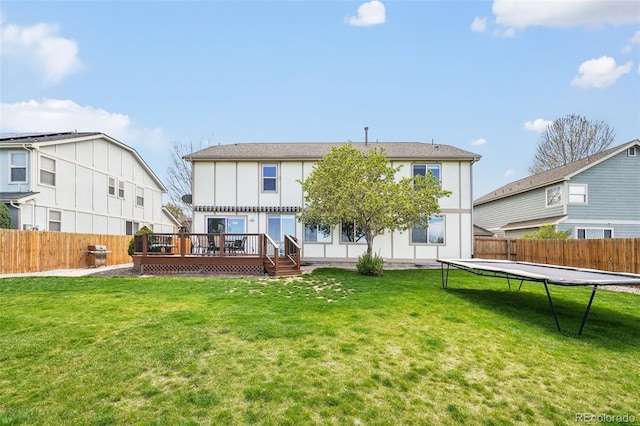 6565 W 99th Ave, Broomfield, CO 80021 - back of house featuring a lawn, a fenced backyard, a trampoline, and a wooden deck