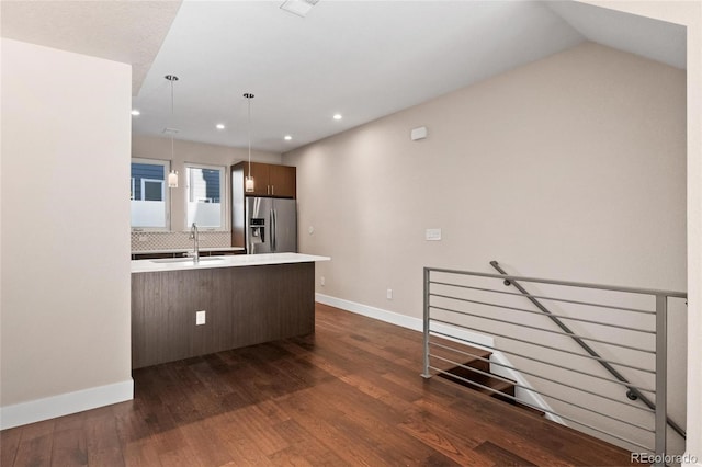 kitchen featuring dark hardwood / wood-style flooring, decorative light fixtures, stainless steel fridge, sink, and decorative backsplash