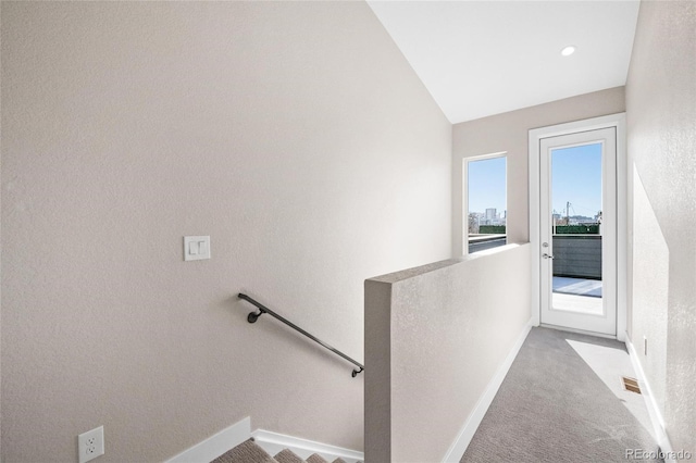 hallway featuring lofted ceiling and light colored carpet