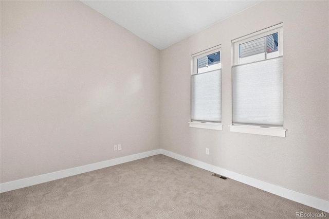 unfurnished room featuring lofted ceiling and light colored carpet