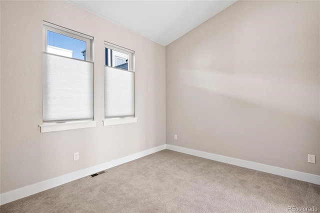 carpeted empty room featuring lofted ceiling