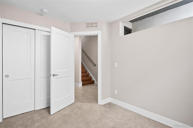 unfurnished bedroom with a closet and light colored carpet