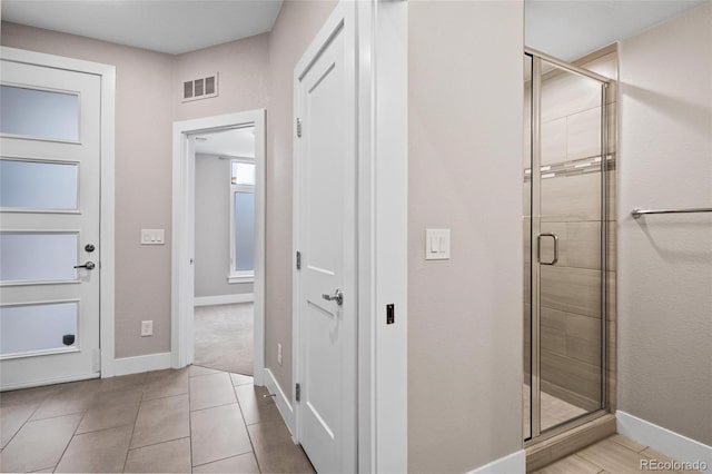 bathroom with tile patterned floors and a shower with door