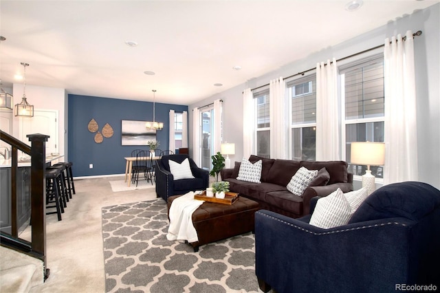 carpeted living room with an inviting chandelier