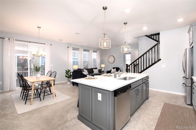 kitchen featuring decorative light fixtures, gray cabinetry, stainless steel appliances, sink, and a center island with sink