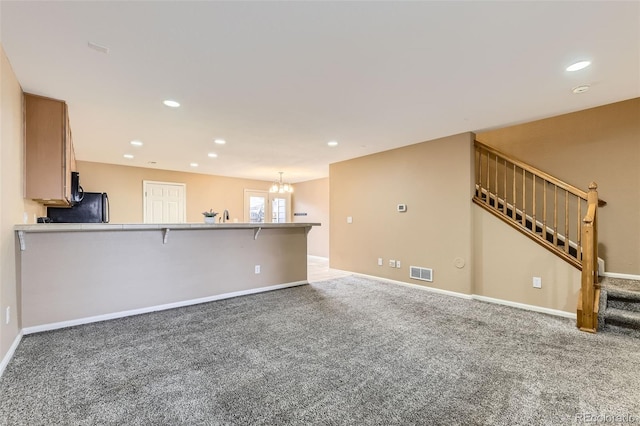 unfurnished living room with carpet and a notable chandelier