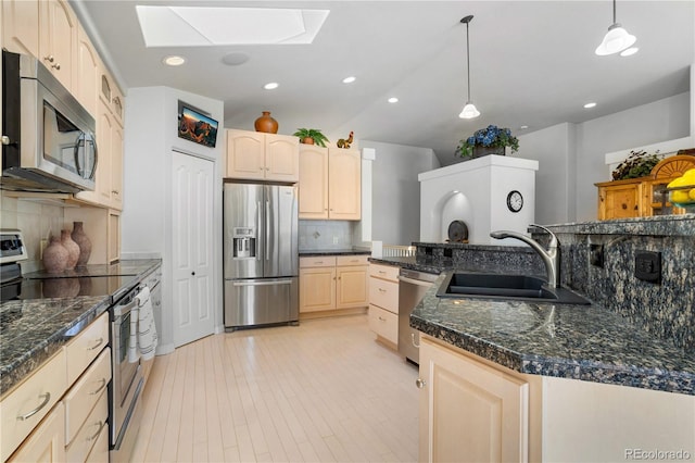 kitchen featuring appliances with stainless steel finishes, a skylight, tasteful backsplash, sink, and hanging light fixtures