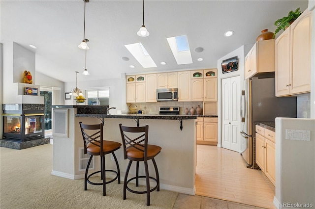 kitchen featuring lofted ceiling, stainless steel appliances, a kitchen breakfast bar, and hanging light fixtures