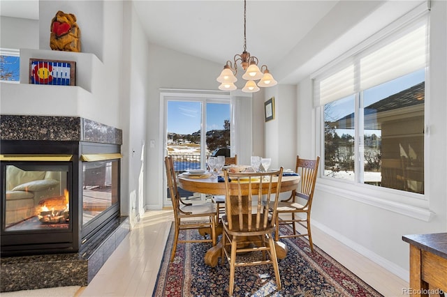 dining space with hardwood / wood-style flooring, a tiled fireplace, an inviting chandelier, and a wealth of natural light