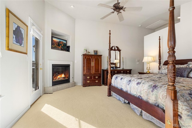 bedroom featuring a tile fireplace, light colored carpet, and ceiling fan